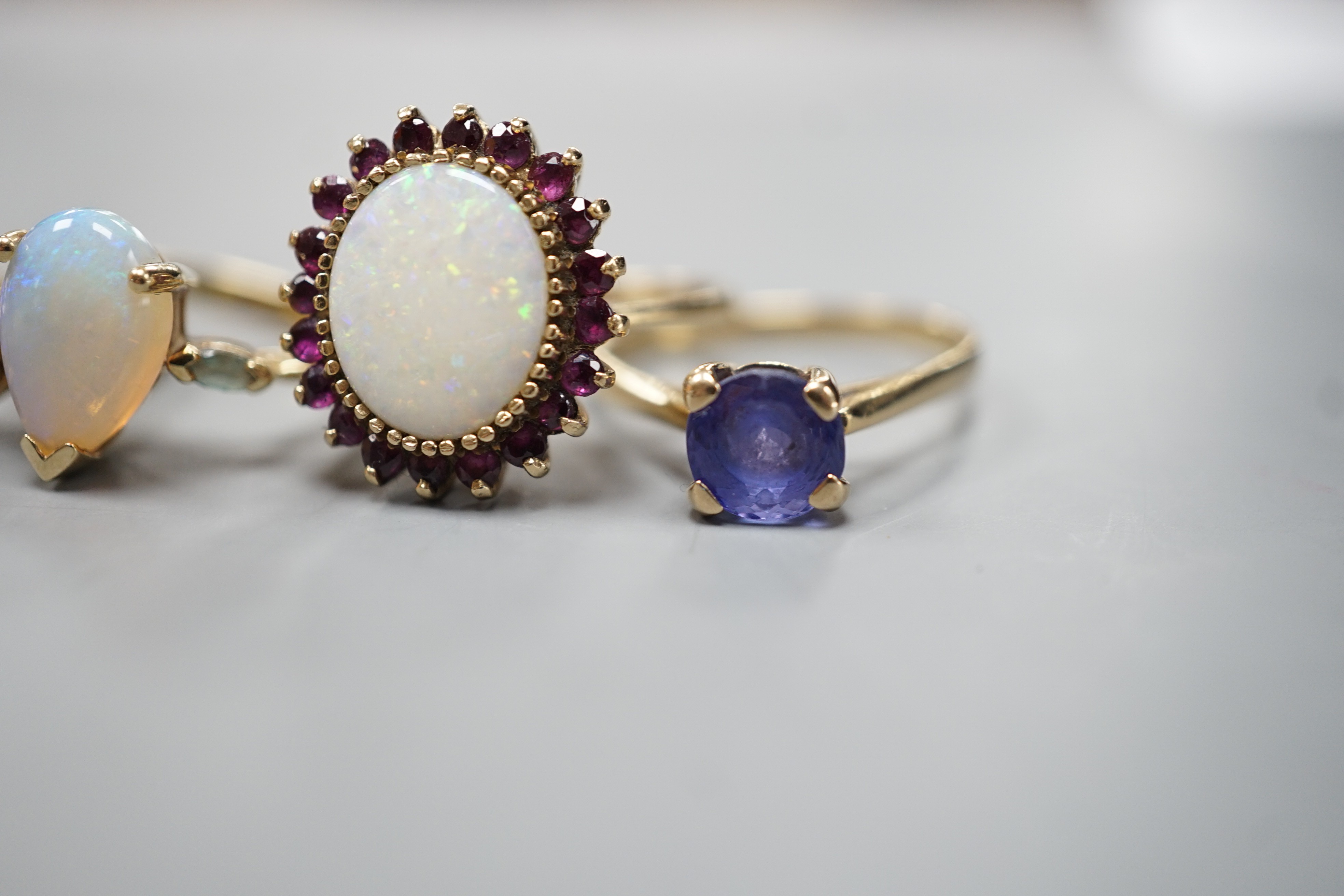 Five assorted modern 9ct gold and gem set dress rings, including white opal and garnet oval cluster, white opal and diamond chip and single stone white opal